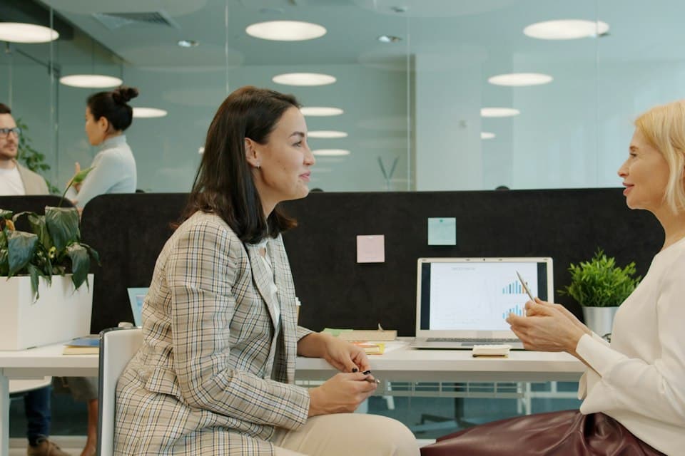 Two colleagues in a mentoring conversation at a desk