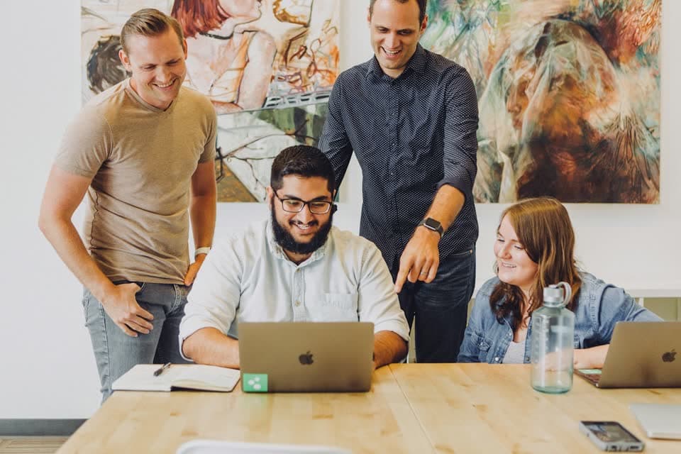 Four colleagues around a laptop in a bright office