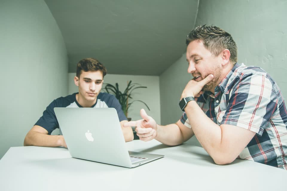 Two colleagues discussing a deal at a laptop