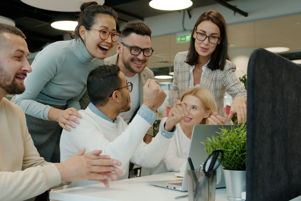 A team celebrating a result at their desks