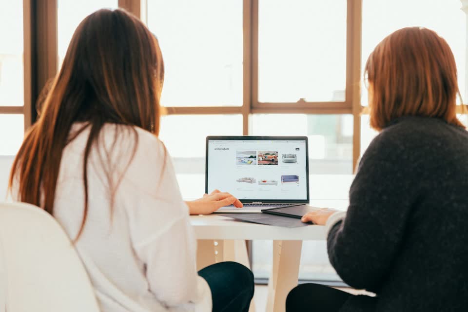 Two colleagues reviewing a laptop together