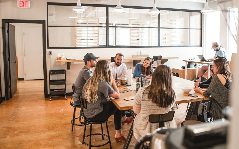 A team talking around a long table in a sunlit office