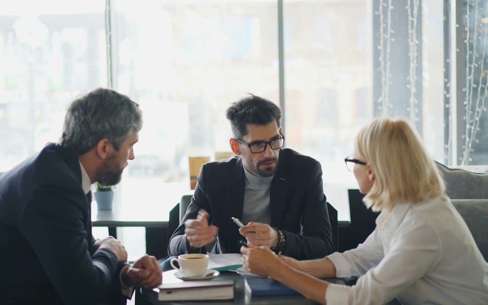 Three colleagues discussing documents around a table
