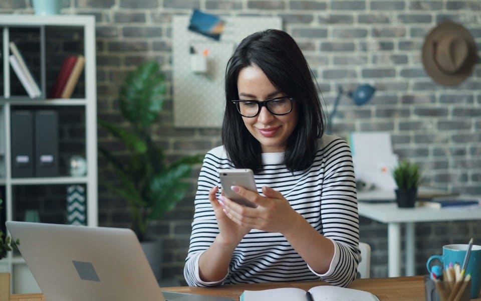 A woman checking her phone at her desk
