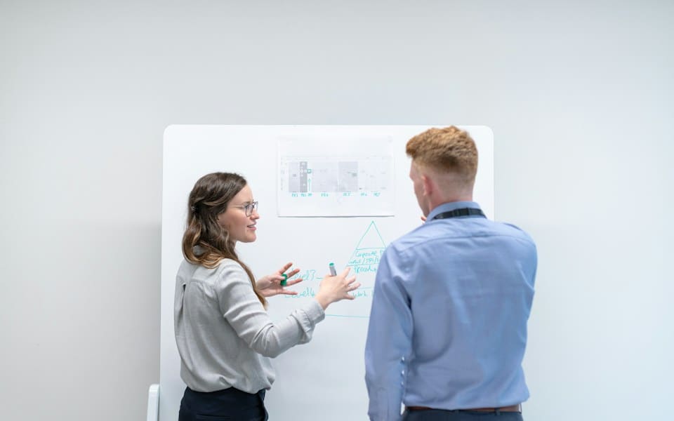 Two engineers talking through a design at a whiteboard